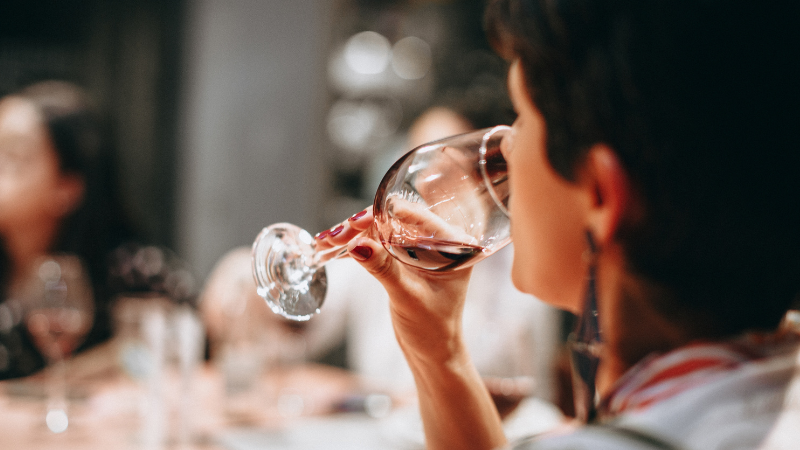 Woman holding a glass of red wine, reflecting on the effects of alcohol on mental health and wellbeing