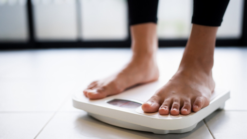 Woman standing on a white weighing scale, representing health, body awareness, and support for wellbeing.