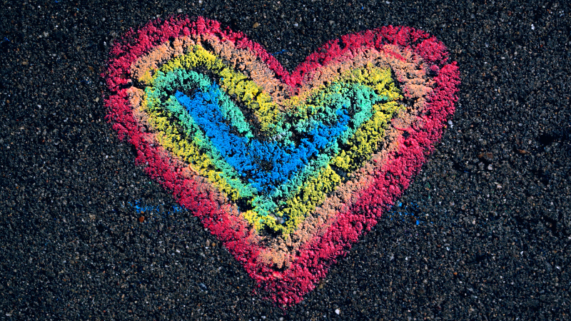 Chalk rainbow heart drawn on tarmac, symbolising LGBTQ+ pride, inclusivity, and support for mental health.
