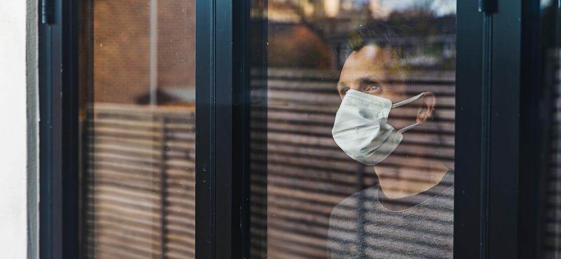 Man with Mask Looking Out of Window
