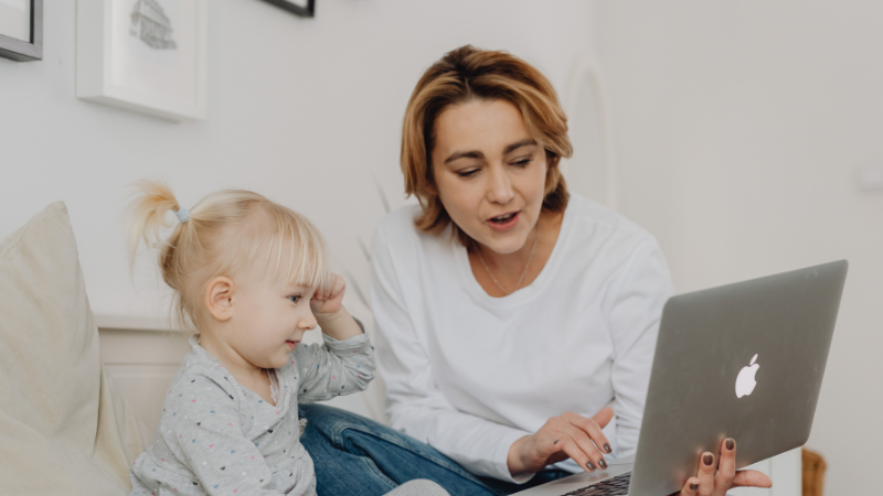 A mother with her toddler looking at a laptop together.