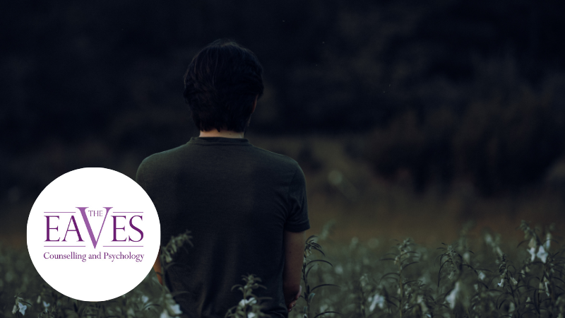 Back of a man standing alone in a field, symbolising loneliness and introspection – The Eaves Counselling and Psychology