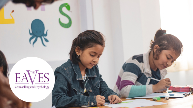 Two young schoolgirls sitting at a table writing on paper, representing primary school learning and childhood anxiety.