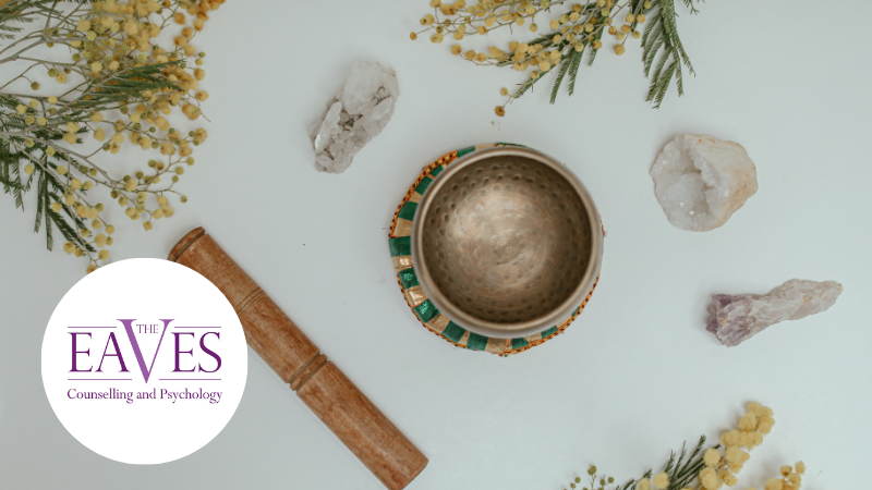 Mindfulness still life with singing bowl, crystals and calming natural elements on a pale background.