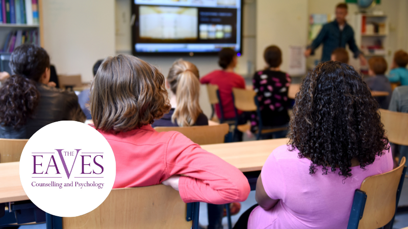 Children in a classroom watching a teacher and smart screen whiteboard during a CBT-based therapy session