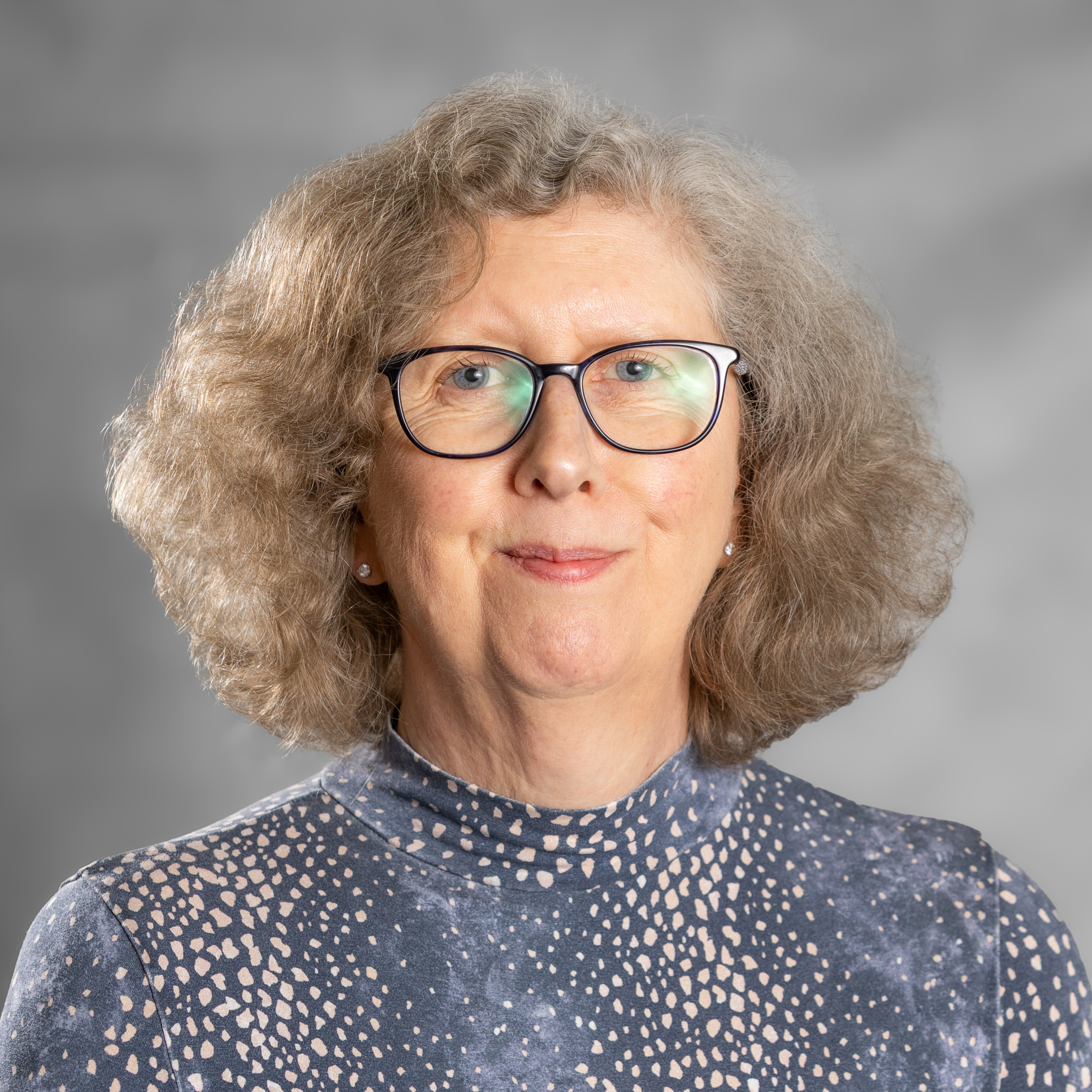 Image of Anne Lawrance-Anderson, a psychodynamic counsellor working with adults experiencing anxiety, infertility and trauma, is a woman with short curly hair and is wearing a blue top.