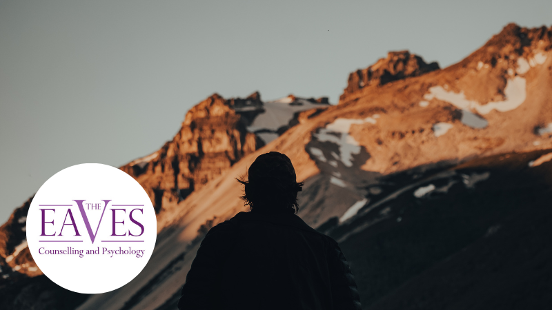 Silhouette of a man standing in front of a mountain landscape, symbolising self-esteem, reflection and personal growth.