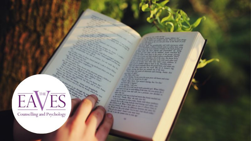 Hands holding a book in a forest, symbolising reflection, grief therapy and healing through reading.