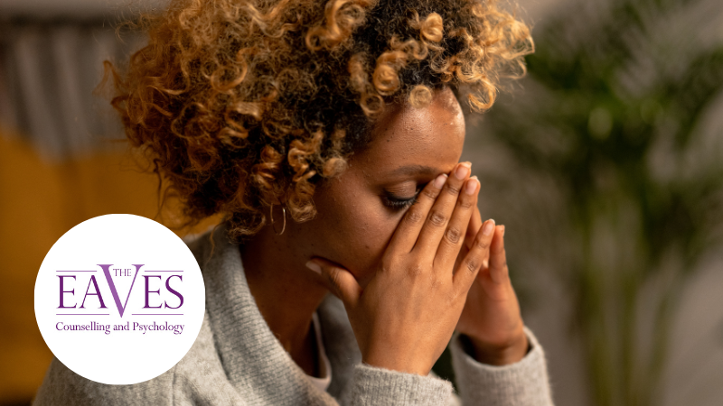 A woman sitting with her head in her hands, appearing stressed or overwhelmed.