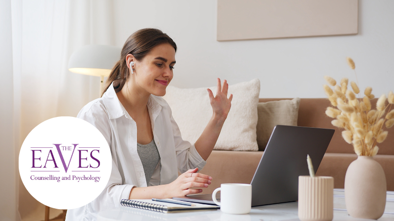 A therapist smiling at her laptop while recording a video in a calm, professional setting