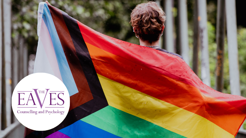 Young woman seen from behind holding a pride flag, symbolizing inclusion, identity, and neurodiversity acceptance.