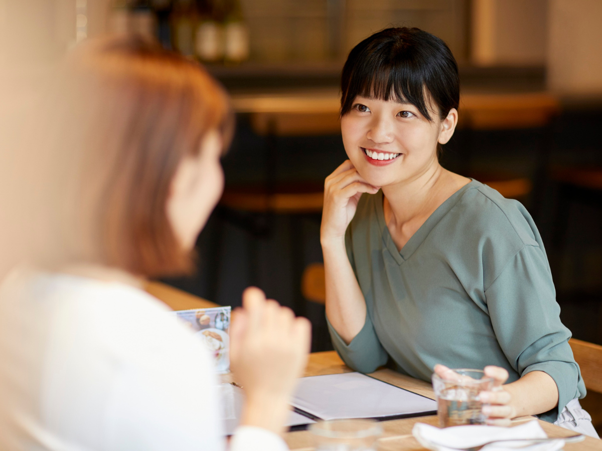 Two women sitting together at a table, having a friendly and engaged conversation.