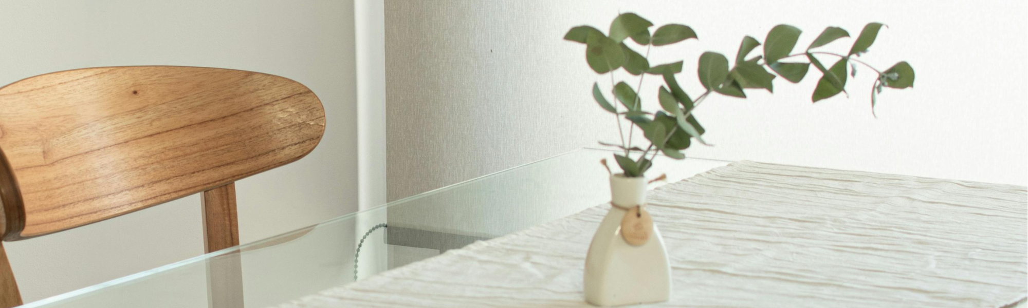 Dining table with wooden chairs and a vase of eucalyptus, symbolising calm and mindful eating environment.