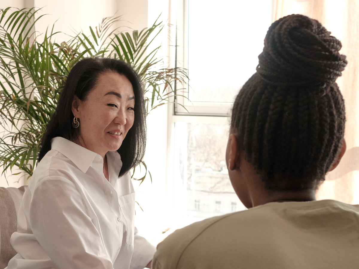 Therapist speaking to a client during a session, with the client’s back visible.