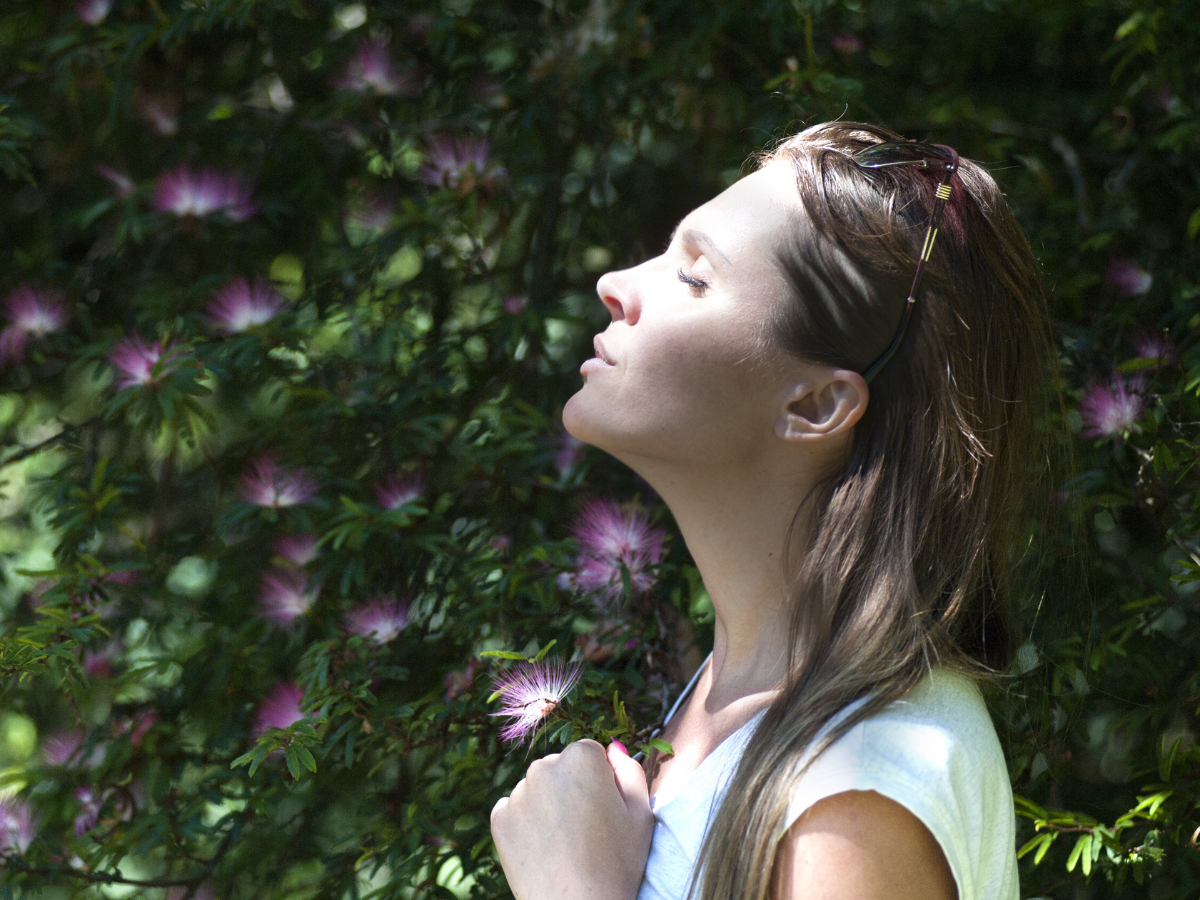 Woman with eyes closed taking a deep breath outdoors, symbolising calm, emotional regulation and the therapeutic process