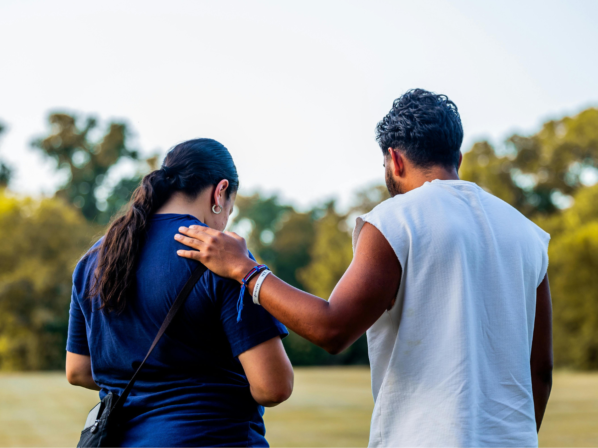 Person being supported by a friend, hand on shoulder, symbolising seeking help and stress management