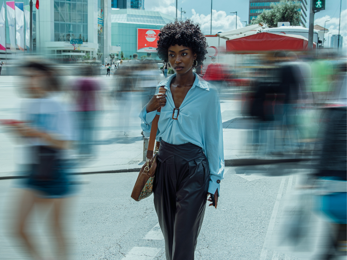 Woman walking on a busy street, in focus while surroundings and other people are blurred, representing feeling isolated or anxious