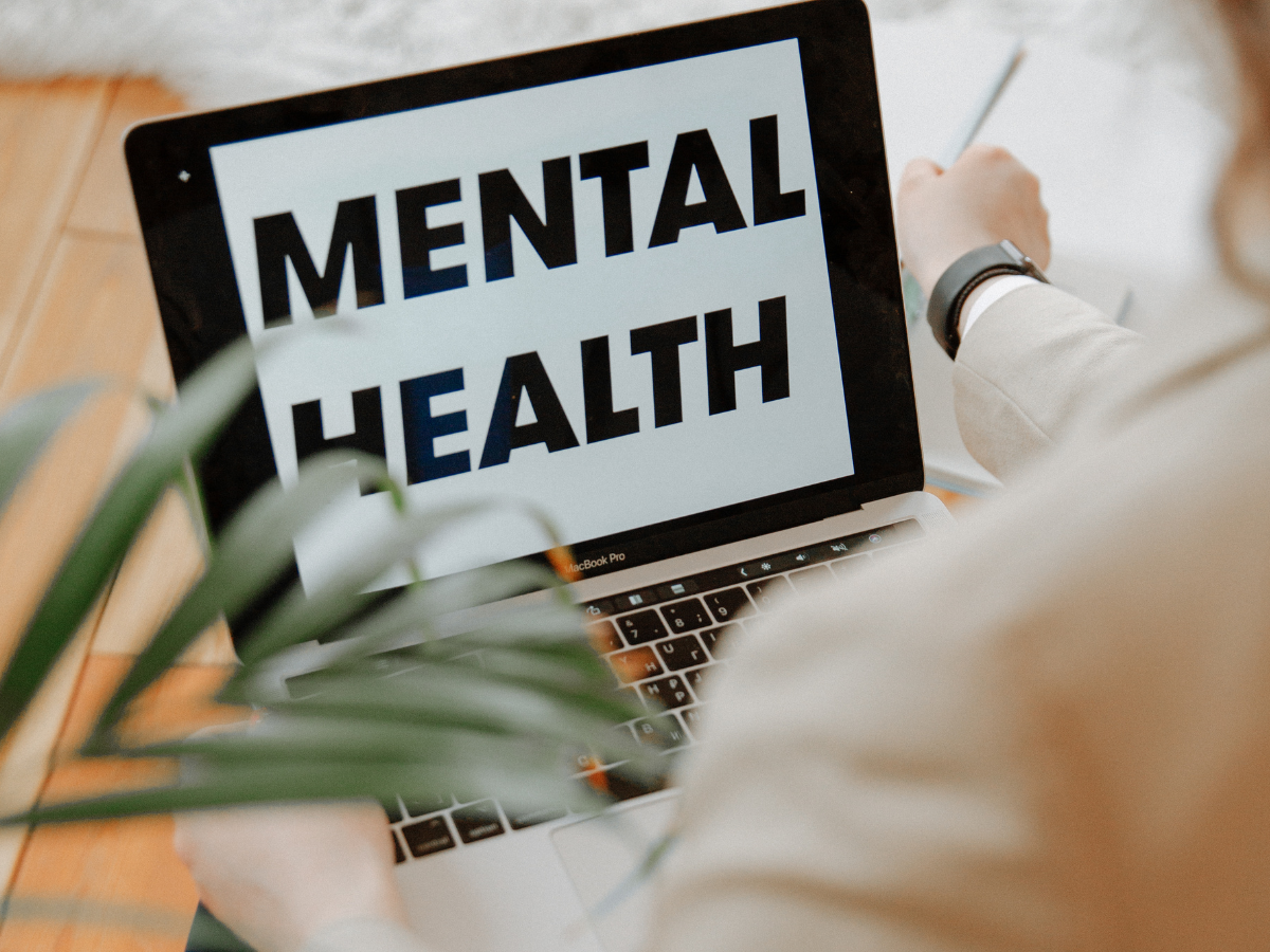 Person holding a laptop displaying “mental health” symbolising Lewis Capaldi’s mental health initiative after Glastonbury 2025.