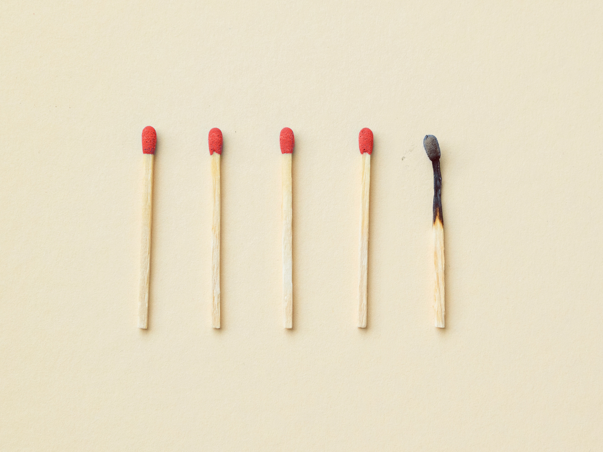 A line of matchsticks with one burnt-out match in the middle — a powerful visual metaphor for burnout, exhaustion, and emotional overwhelm among millennials.