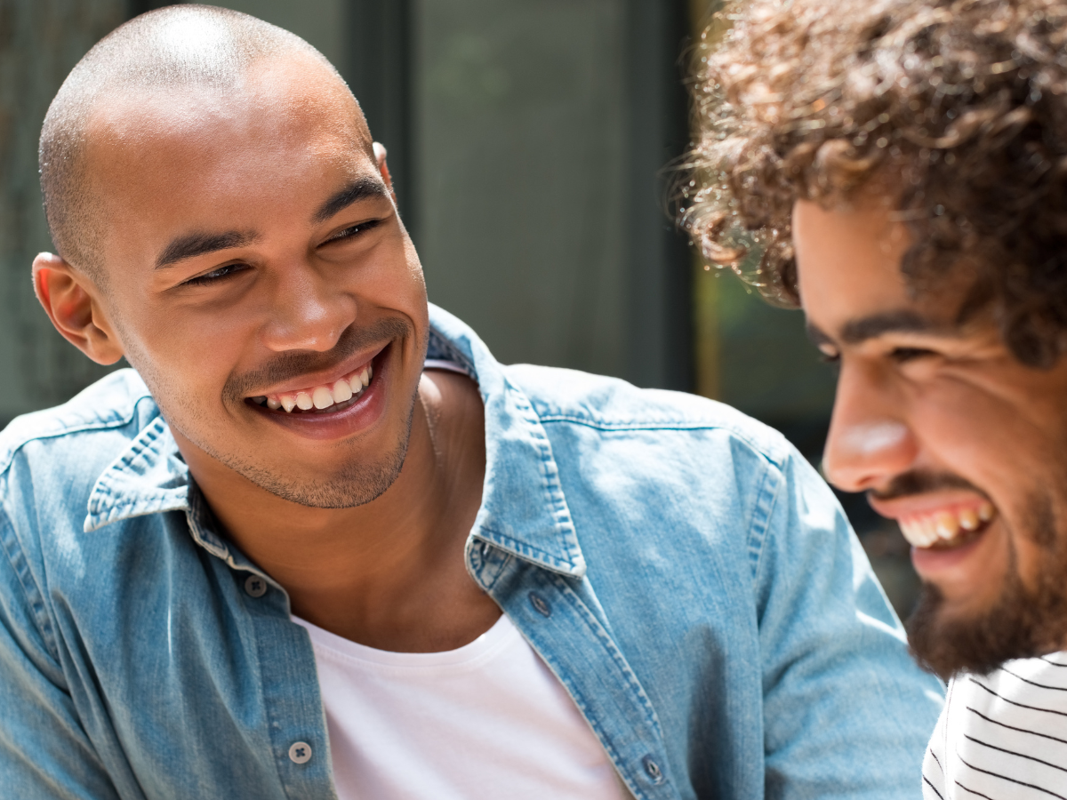 Two male friends sitting and talking openly, showing emotional connection and support — representing mental health awareness and meaningful friendship among millennials.