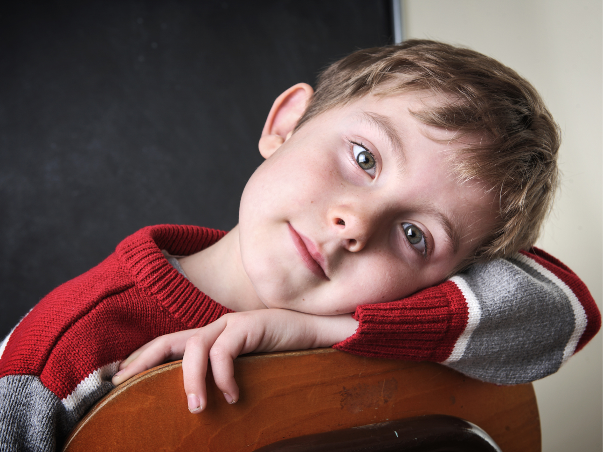 Young boy sitting thoughtfully on a chair during therapy