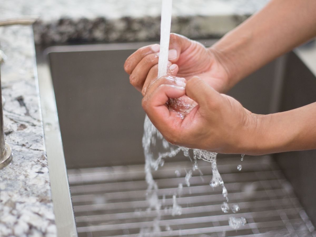 Person washing hands under running water, representing compulsive cleaning behaviours often associated with OCD.