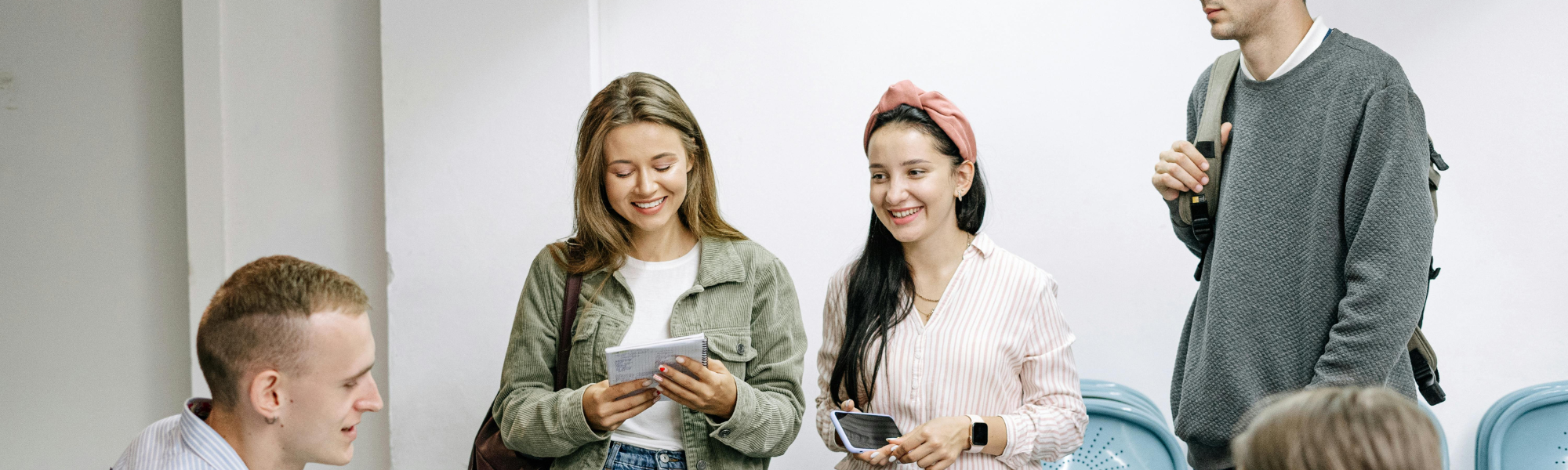 Group of millennials sitting and standing around a table, chatting and laughing casually, enjoying a relaxed social moment
