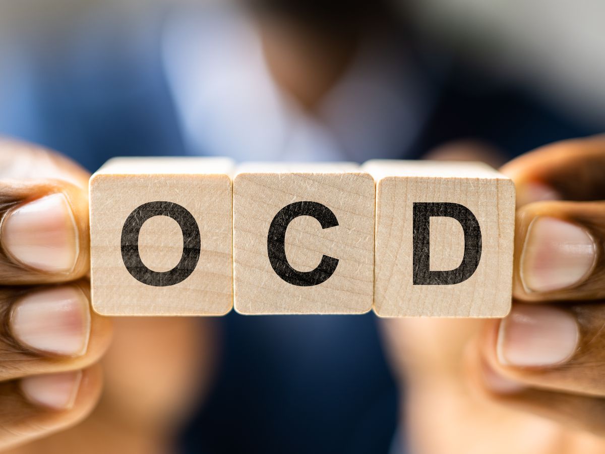 Person holding three wooden blocks with letters spelling “OCD,” symbolising awareness and understanding of Obsessive-Compulsive Disorder.