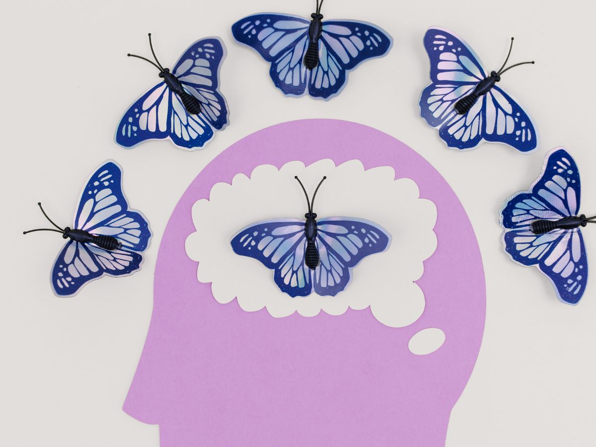 Illustration of a purple head with butterflies around the brain, symbolising mental health, intrusive thoughts, and the possibility of healing from OCD.