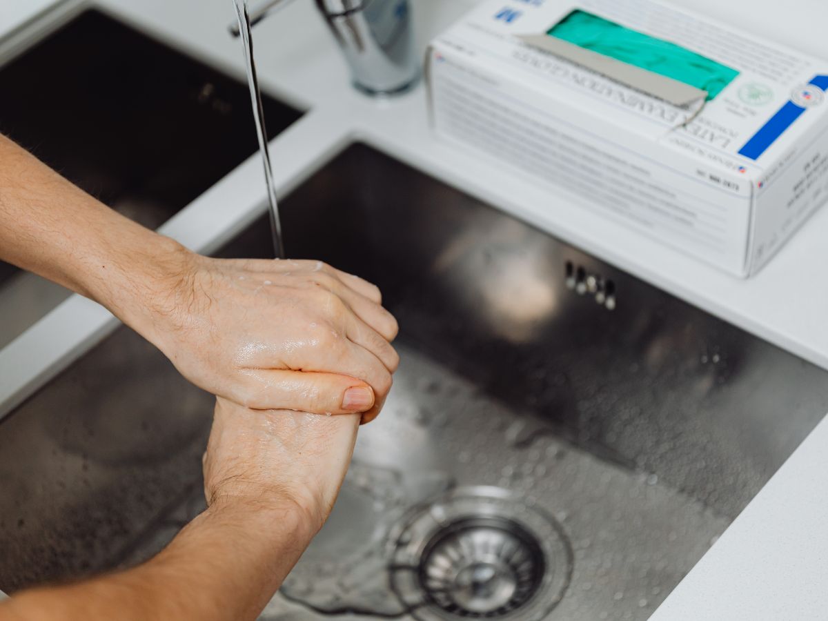 Close-up of hands being washed under running water in a sink, illustrating compulsive handwashing associated with obsessive compulsive disorder (OCD).