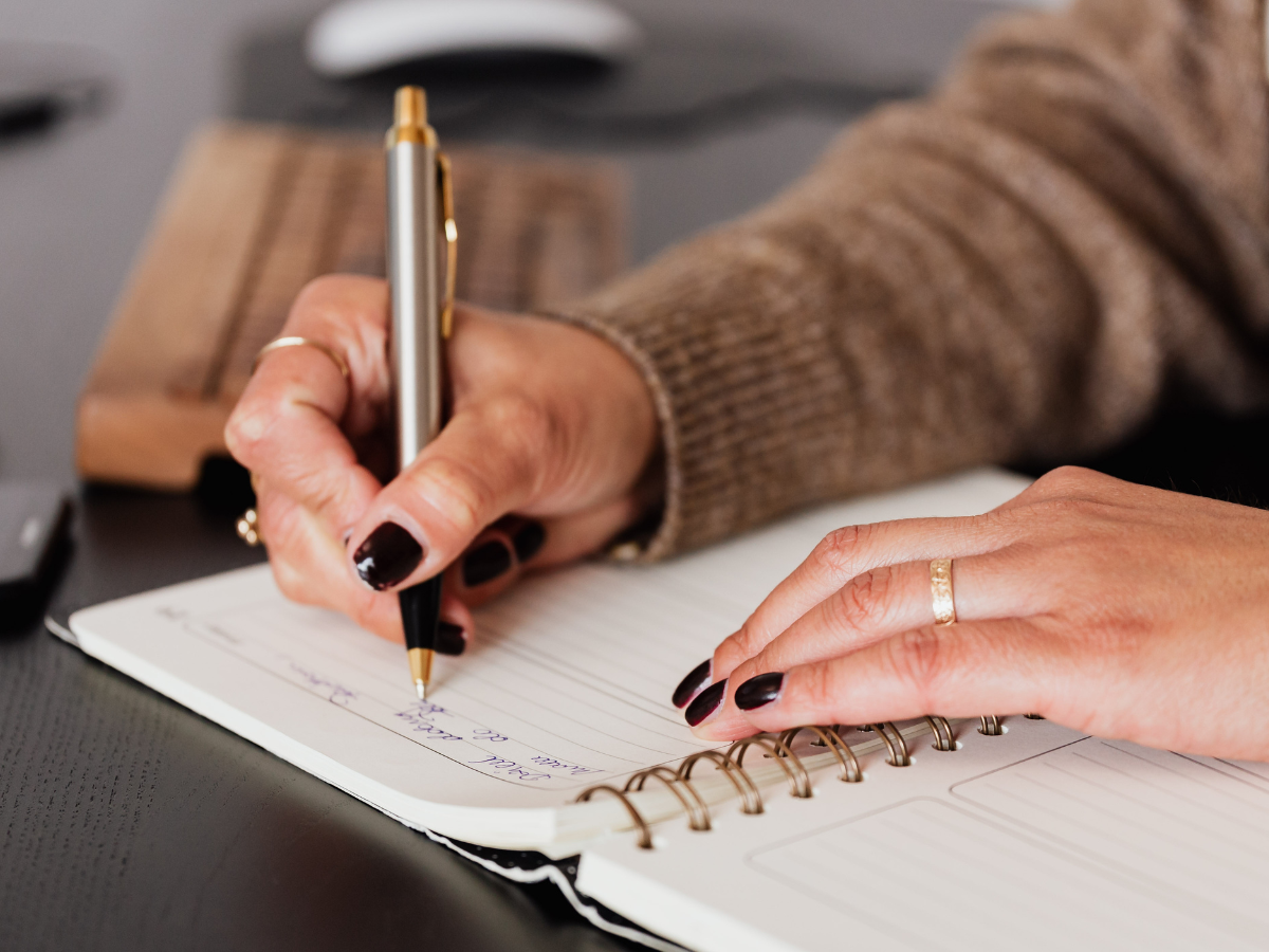 A woman writing in a notebook at a desk, symbolising hidden anxiety, emotional overwhelm, and the quiet mental load carried by high-functioning women.