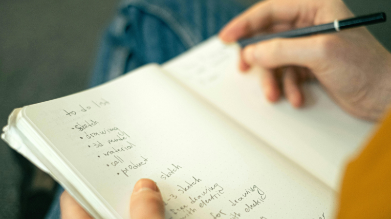 Person feeling overwhelmed while overthinking a long to-do list on paper.