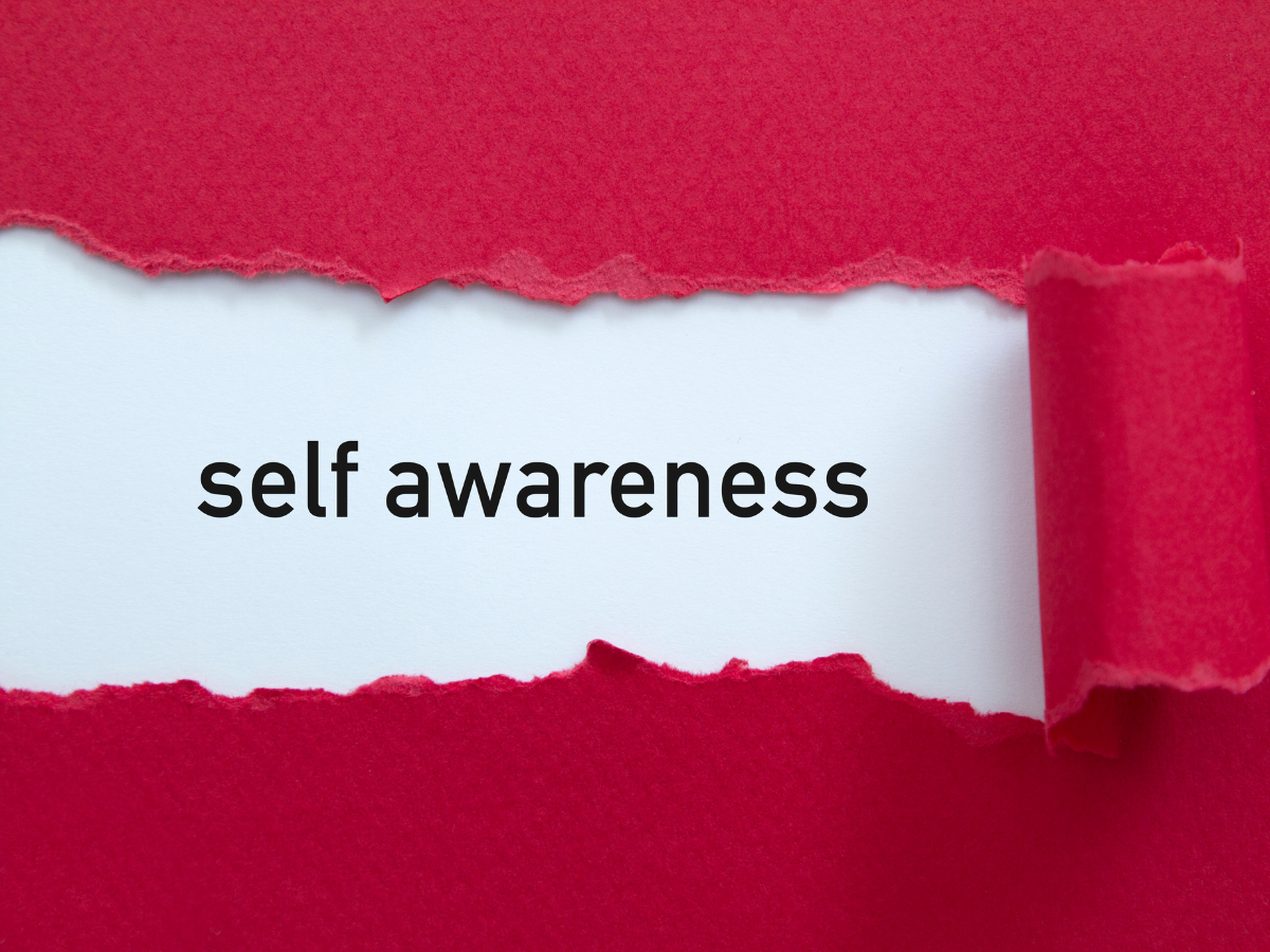 ed paper torn in the middle revealing the words “Self Awareness” underneath