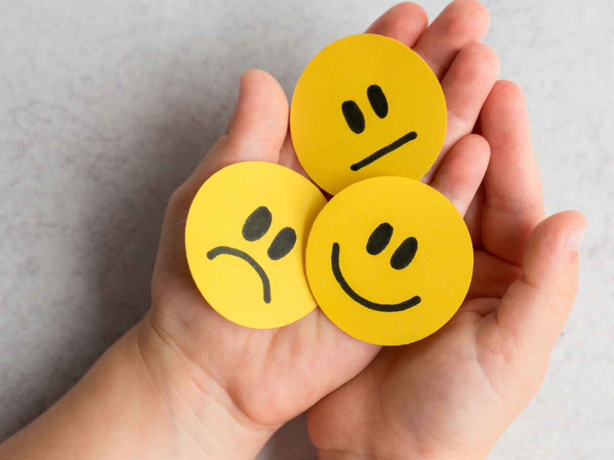 Hands holding smiley faces showing different emotions, illustrating emotional awareness