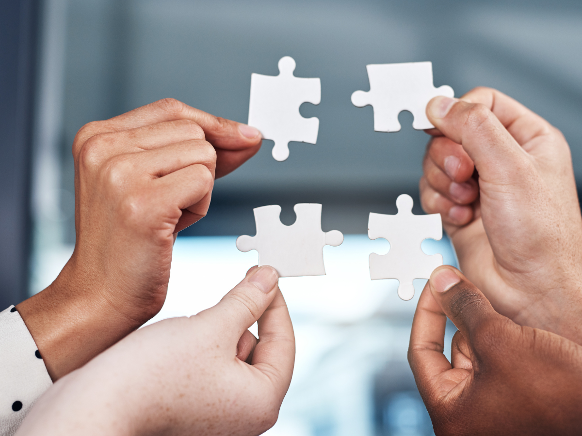 Four hands each holding a puzzle piece fitting together, symbolising putting the DBT techniques together