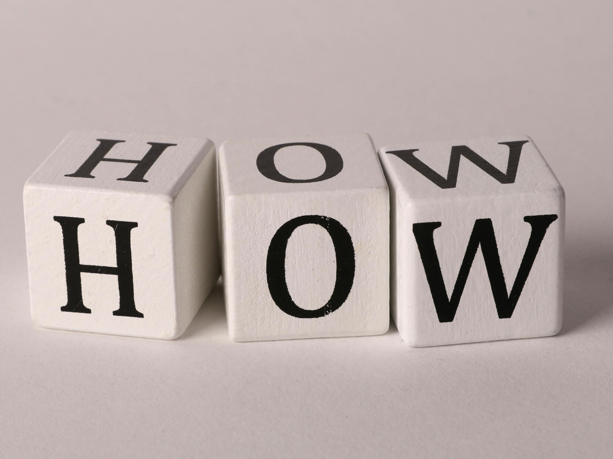 Three dice blocks arranged to spell the word “HOW”