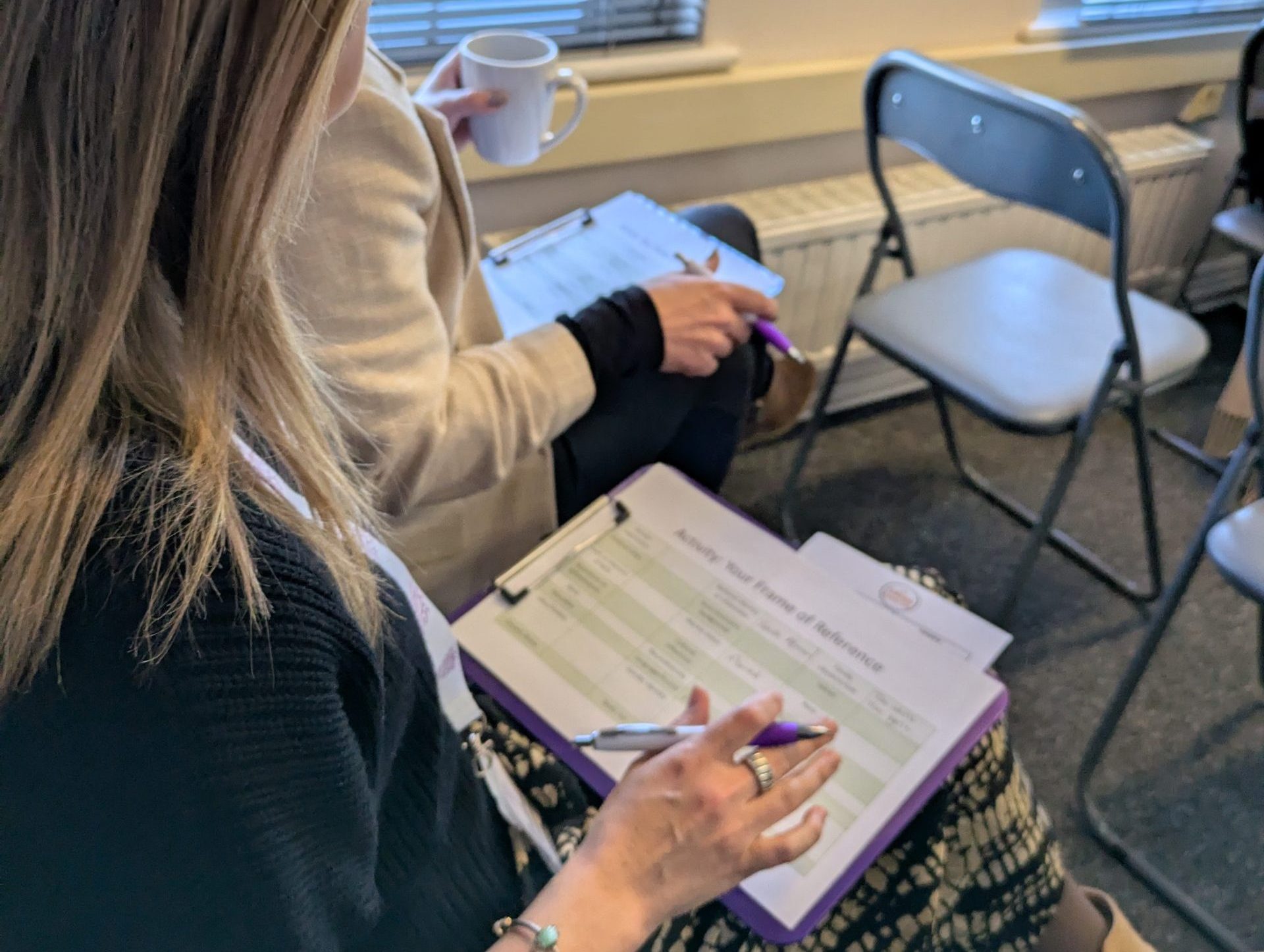Two attendees taking notes during a mental health workshop at The Eaves Counselling in Farnham