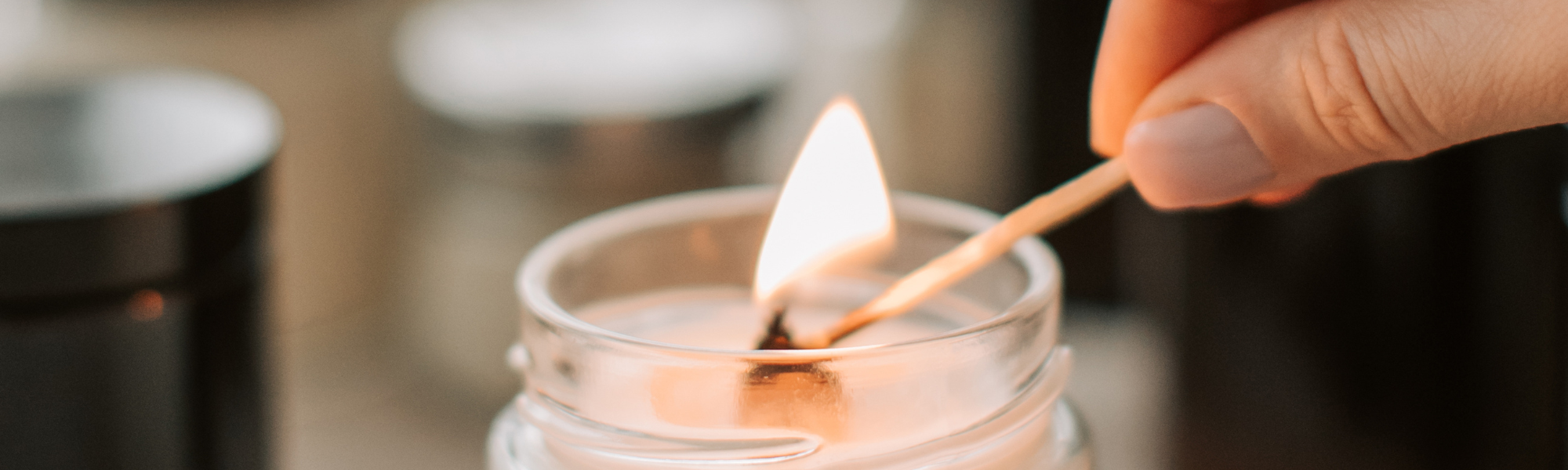 A woman lighting a white candle with a match, symbolising hope, calm and emotional healing.