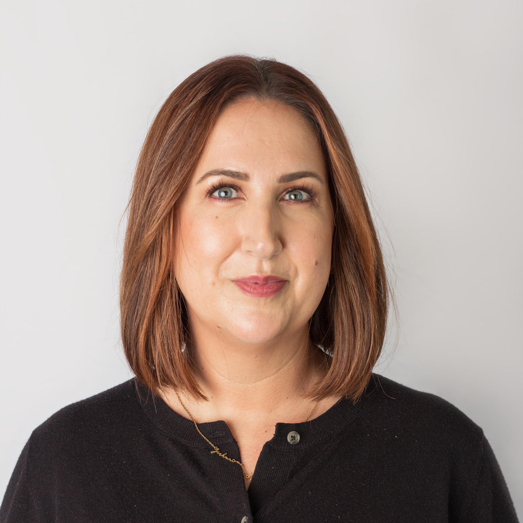 Professional headshot of Vikki, a woman with short brown bob hair wearing a black top, smiling against a white backdrop.