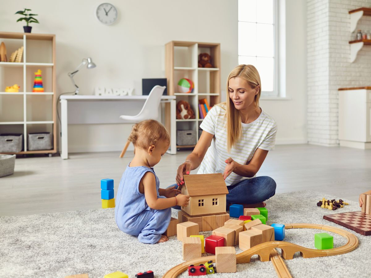 Mom and child playing together with wooden building blocks at home