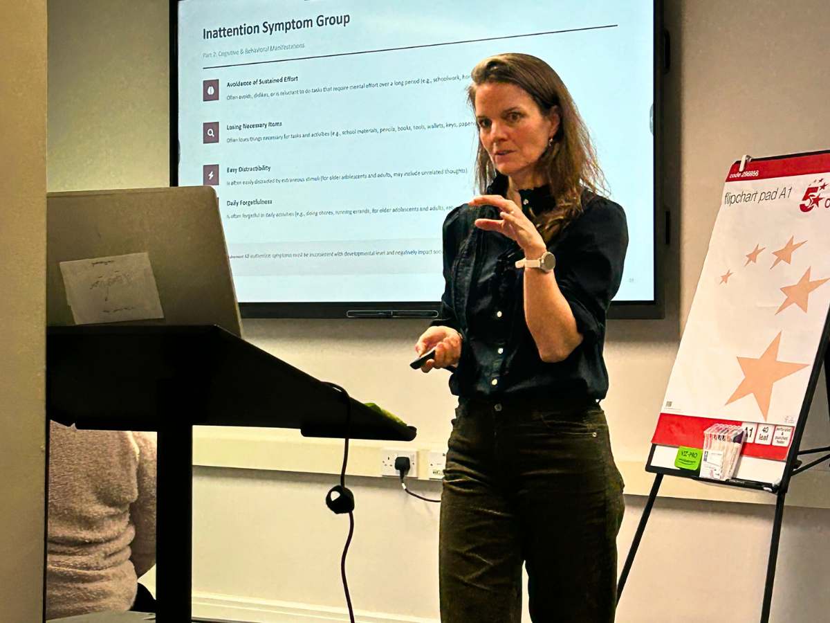 Presenter leading a Counselling CPD workshop with a whiteboard, large presentation screen, and laptop on a stand at The Eaves