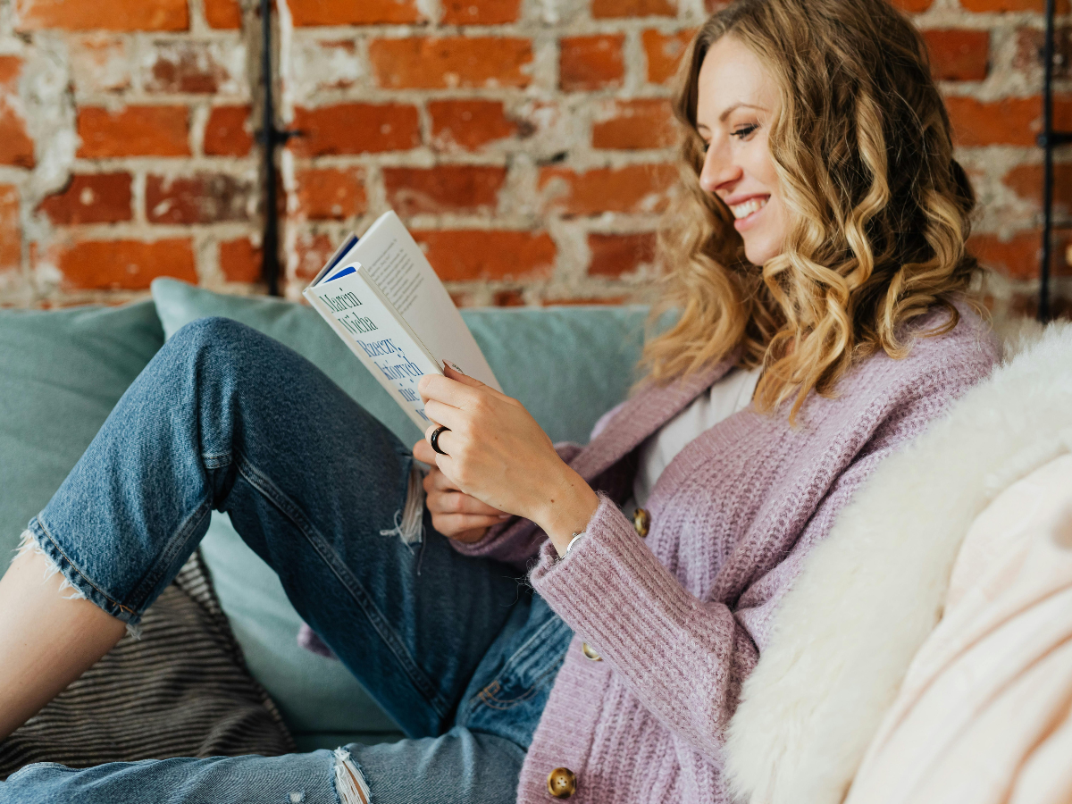 Woman reading a book on a comfy sofa, relaxing and unwinding