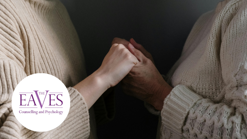 Two women, one middle-aged and one older, standing close together and holding hands in a supportive gesture, representing emotional connection and reassurance.