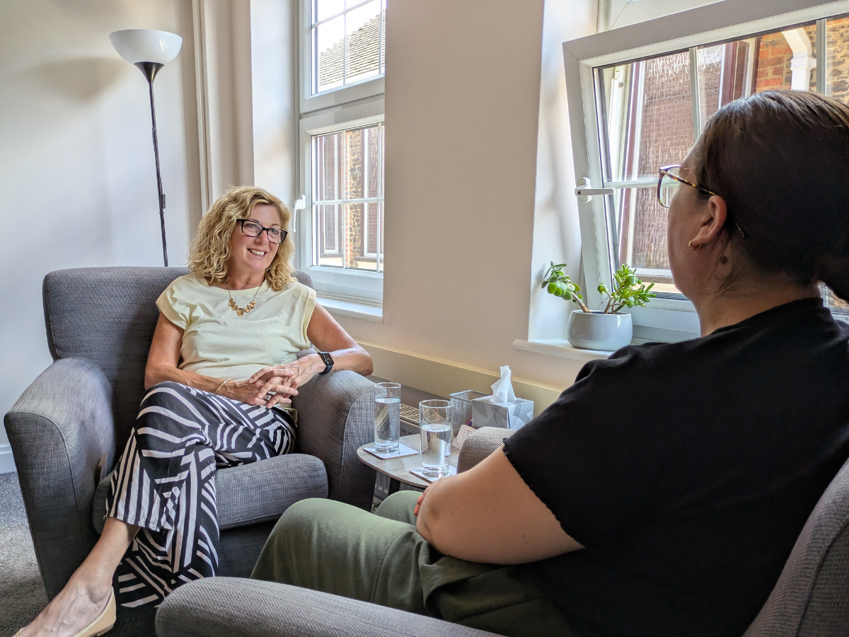 Therapy session setup with neutral grey chairs and a small brown table with glasses of water