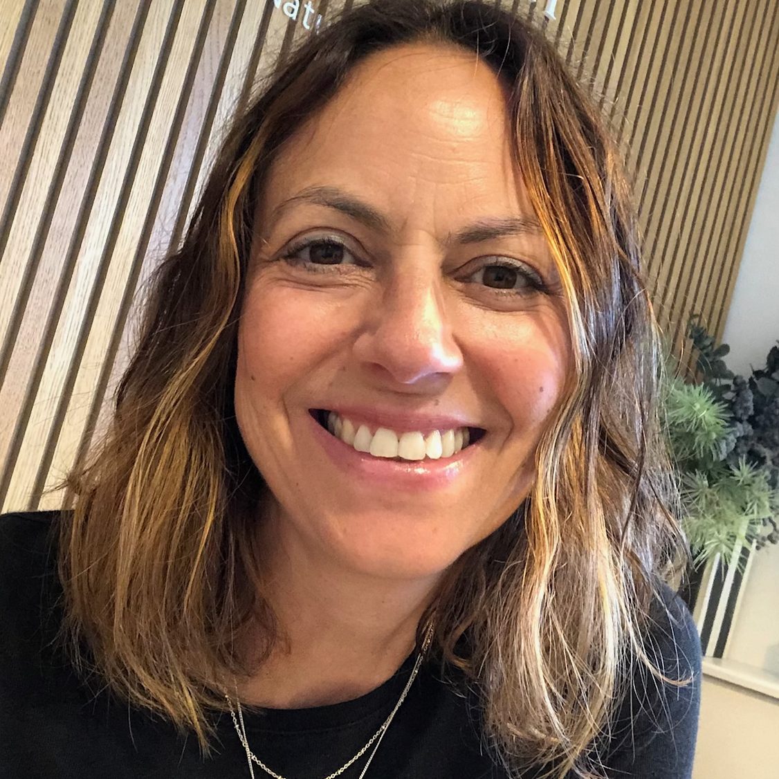 Decima Hendrick, integrative counsellor and psychotherapist for adults, a woman with mousy brown hair in front of a wooden panelled background.