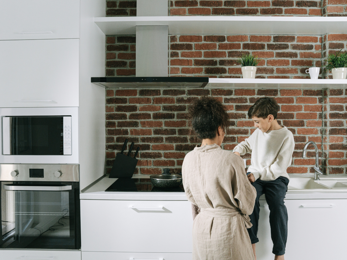 Mother and son talking together in kitchen, child sitting on counter sharing thoughts in a supportive home environment