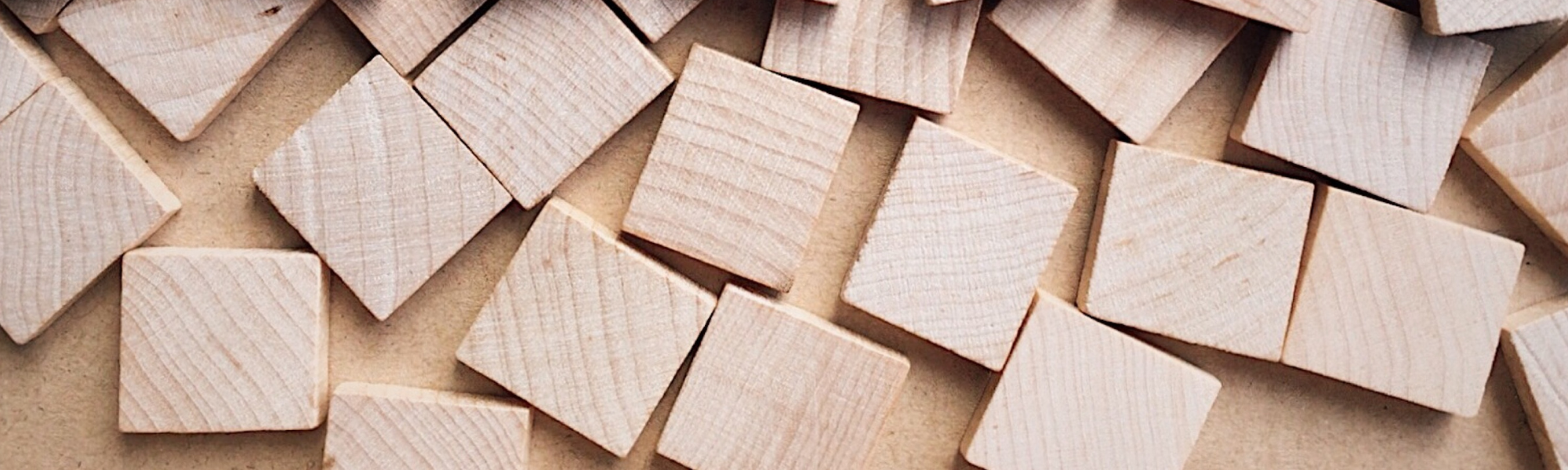 Scrabble tiles arranged on a pile of blank wooden tiles, with no words spelled out.