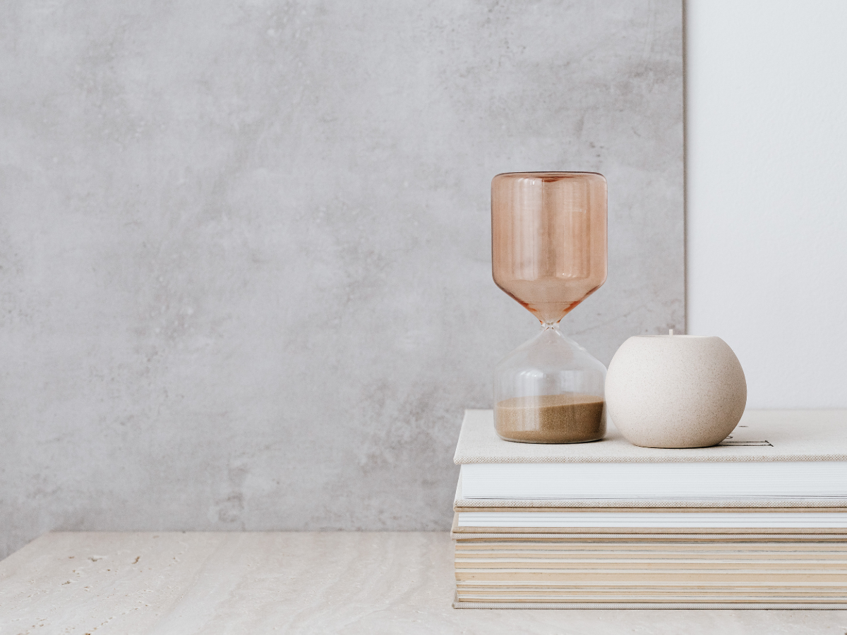 Hourglass and white candle on a stack of books, symbolising reflection, personal growth and the therapeutic journey.