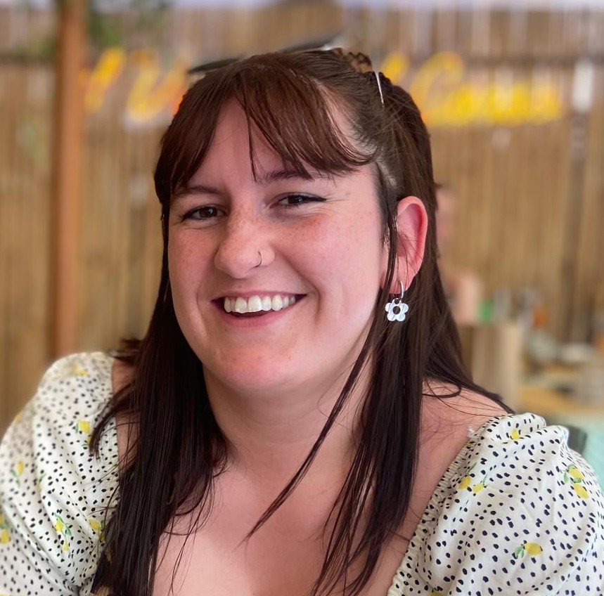Image of Maria Kay, a counsellor and psychotherapist with brown hair and a floral dress supporting clients aged 14 and above using collaboration and curiosity to build meaningful change.