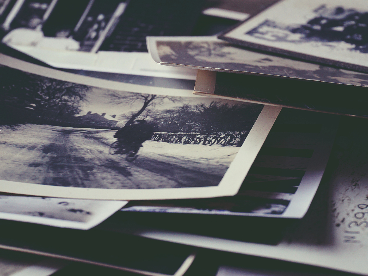 Stack of old black-and-white photographs symbolising memories, life experiences and personal history.